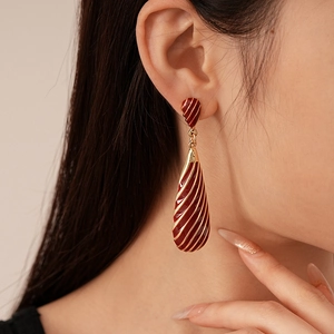 Close-up of model wearing red zebra stripe teardrop earrings with gold details