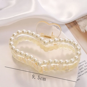 Detail of 9.5cm heart hair claw clip with white pearls on a silk background