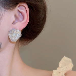 Detailed close-up of irregular resin stud earrings with silver and gold foil on model
