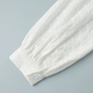 Détail du poignet blanc avec broderie florale délicate et bouton en résine élégant