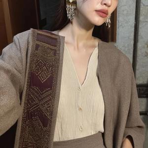 Detail of gold beaded tassel earrings paired with a brown textured cardigan set