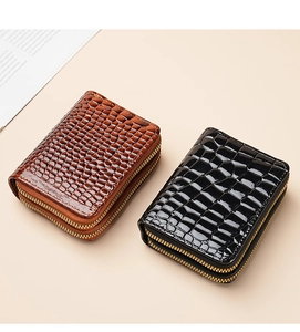 Detail of black and brown crocodile pattern wallets with golden zippers on beige backdrop