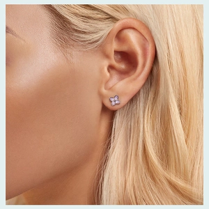 Close-up of a model wearing a delicate purple flower stud earring in 925 sterling silver