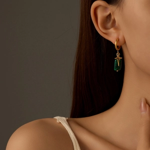 Close-up of a green malachite drop earring with gold star charm on model's ear
