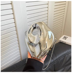 Irregular fluid silver acrylic clutch bag held by model with metal chain strap detail