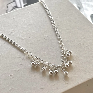 Minimalist 925 sterling silver beaded bracelet with dangling ball fringe on textured box