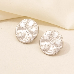 Detailed shot of matte silver earrings with embossed sun, moon and star patterns