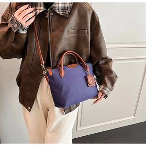 Detail of purple nylon tote bag with leather flap and detachable shoulder strap worn on side