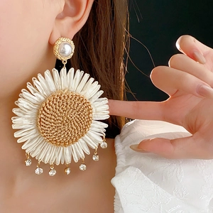 Detail of woven sunflower earring with crystals and pearl stud on a model