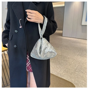 Sac à main argenté à paillettes au design triangulaire porté par un mannequin