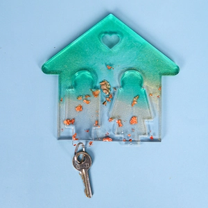 Dettaglio dello stampo per portachiavi in resina verde a forma di casa con foglia oro