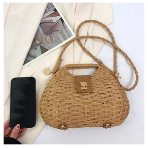 Dettaglio di una borsa in paglia intrecciata con chiusura a rotazione dorata e texture