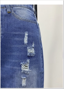 Vista macro dei dettagli della gonna in denim con fori sfilacciati e cuciture delle tasche