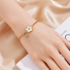 Detail of a gold-plated flower bracelet with blue turquoise bead on pink silk background