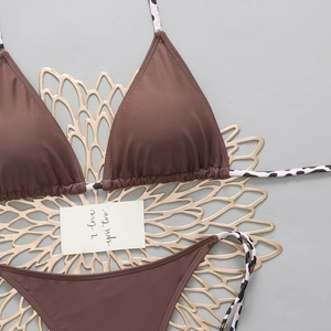 Flat lay of brown bikini set with leopard print straps on a stylish metallic backdrop