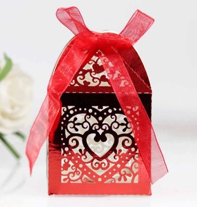 Close-up of red laser-cut wedding favor box with heart patterns and silk ribbon bow