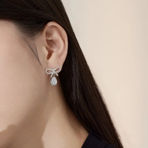 Detailed close-up of S925 silver bow drop earrings with sparkling cubic zirconia inlay