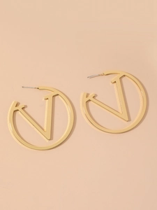 Detailed close-up of large golden metal hoop earrings with a cutout V shape design