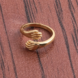 Creative gold plated copper hugging hands open ring shown from a top-down view on leather