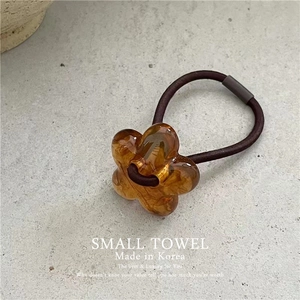 Detailed macro view of amber acrylic flower charm on brown elastic hair scrunchie