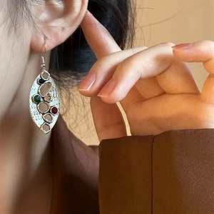Gros plan de boucles d'oreilles ovales martelées vintage avec pierres colorées sur un modèle