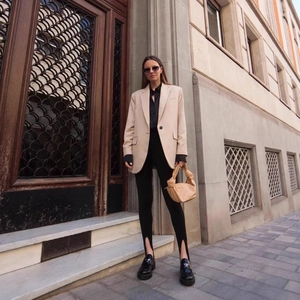 Women's apricot oversized blazer with black slit trousers and platform loafers in city street