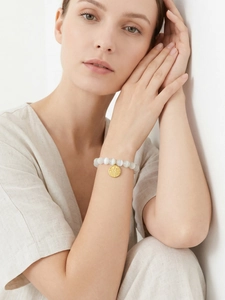 Detail of beaded cat eye stone bracelet with golden Fu character lucky pendant on wrist