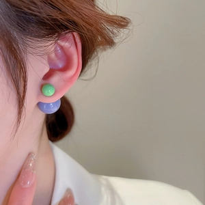 Detail of two-tone green and purple bead earrings shown on a model's ear