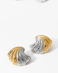 Macro detail of shell-shaped stud earrings featuring golden and silver textured ribbing