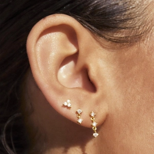 Detailed close-up of 18K gold plated earring set with sparkling zircon on a model ear