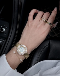 Dettaglio orologio dorato a fiori con castone in cristallo e gioielli coordinati