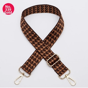 Detail of adjustable wide houndstooth bag strap with gold metal hooks and coffee weave