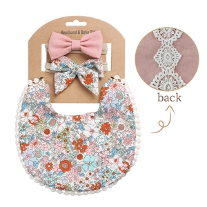 Detail of baby floral bib with lace edges and two matching bow headbands set