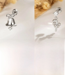 Macro shot of silver titanium steel Christmas bell and candy cane ear piercings