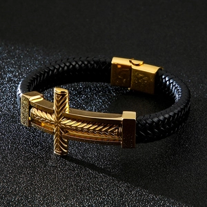 Macro shot of men's black braided leather bracelet with engraved gold cross and buckle