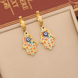 Detail of gold Hamsa hand earrings with colorful rhinestones and blue evil eye charms