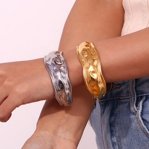 Close-up of hammered textured wide metal cuff bracelets in gold and silver finish