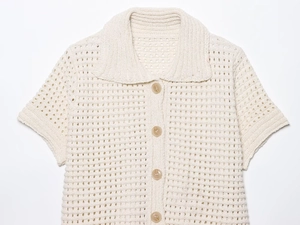 Detail of cream crochet knit cardigan with a classic collar and wood-tone buttons