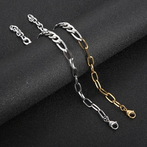 Gold and silver stainless steel Figaro and paperclip link bracelets on black background