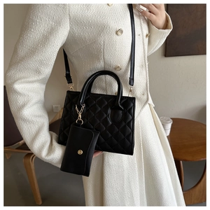 Close-up of black quilted crossbody bag with a matching mini coin purse and shoulder strap