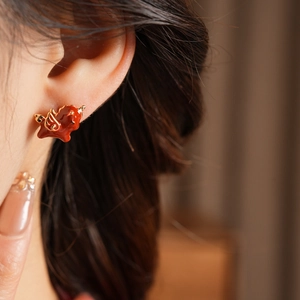 Macro shot of 18k gold plated unicorn stud earring with red enamel and zircon details