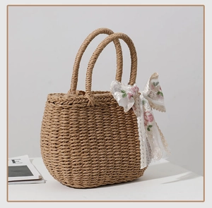 Detail of straw woven handbag with white lace and pink floral ribbon bow decoration