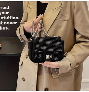 Detail of a black mini chain bag with rhinestone lock and metallic chain strap