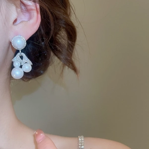 Close-up of elegant pearl drop earrings with sparkling zircon on a female model