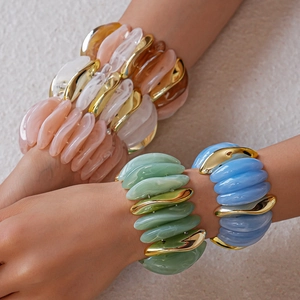 Close-up of chunky acrylic resin bracelets in pastel colors with gold metal accents