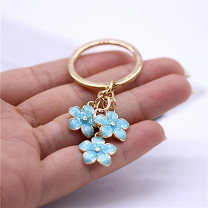 Enamel cherry blossom flower keychain with light blue petals and golden metallic finish