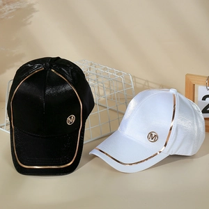 Détail de casquettes en satin noir et blanc avec logo M en métal et liseré brillant