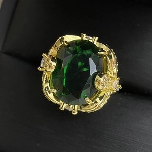 Macro shot of large oval green gemstone and zircon settings on a gold luxury ring