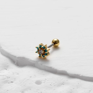 Detail of flower stud earring with blue and clear crystals on a textured stone surface