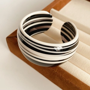 Detailed close-up of striped black and white acetate open cuff bracelet on a tray
